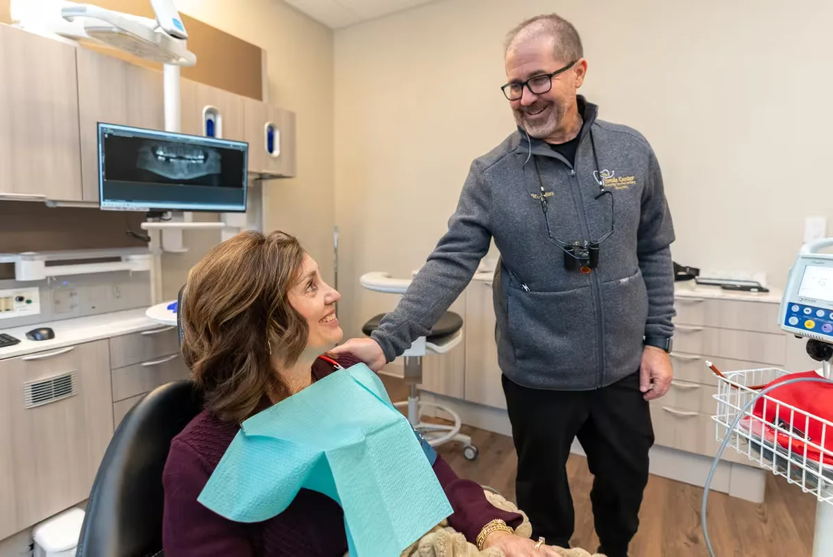 A Smile Center dentist gently examining a relaxed, smiling patient